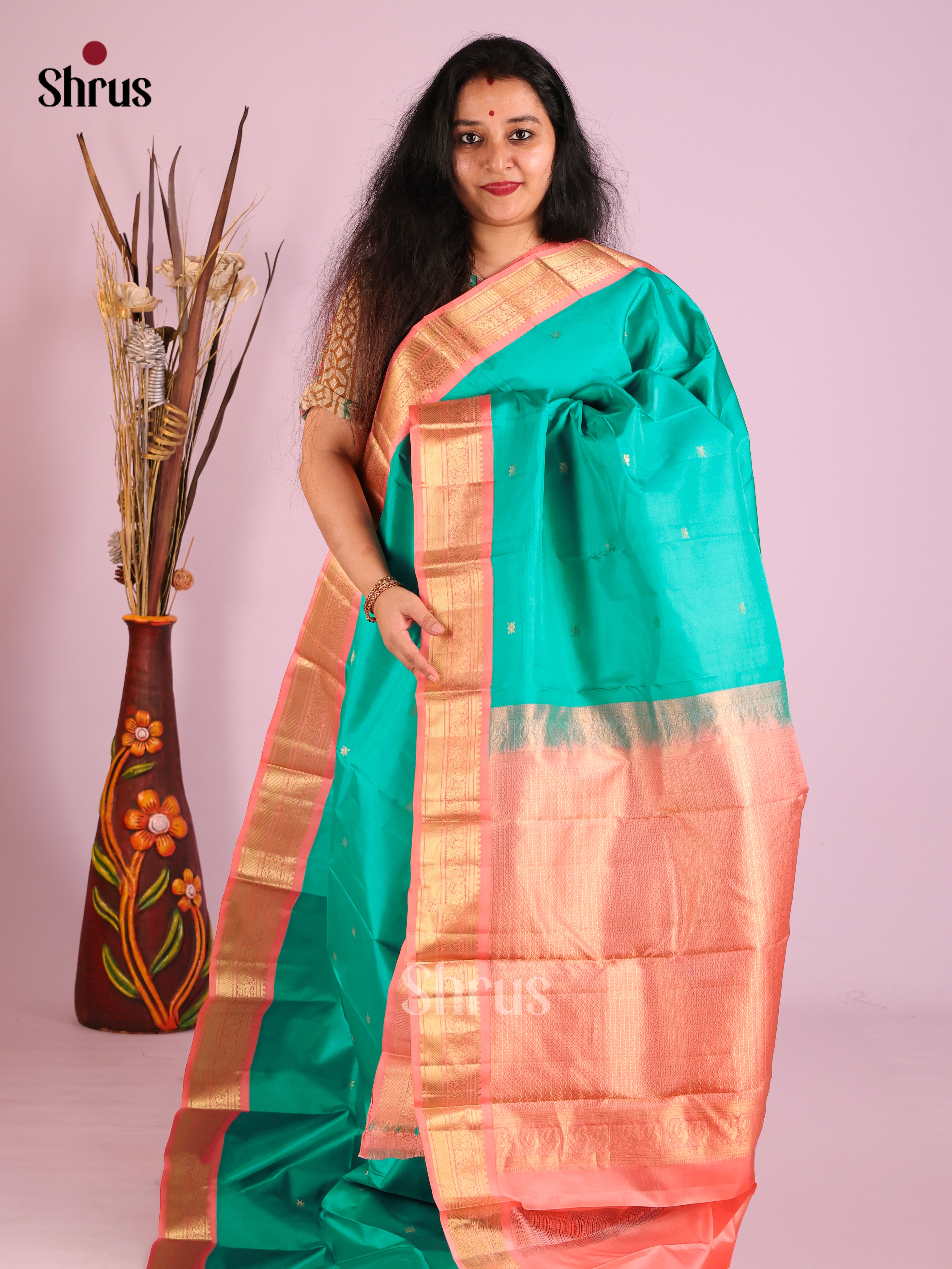 Graceful Green Kanjivaram Saree with Gold buttas & small Peach Zari Woven border